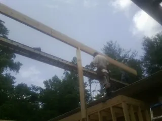 Carpenter setting a ridge beam over a new addition frame — Ice Dam Removal by Roofing Brothers in Coolidge