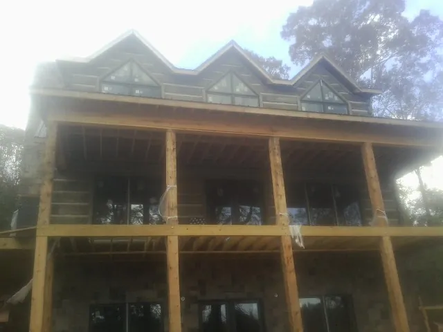 Dormers and porch framing on a large log home under construction — Roof Coating work by our crew in Coolidge